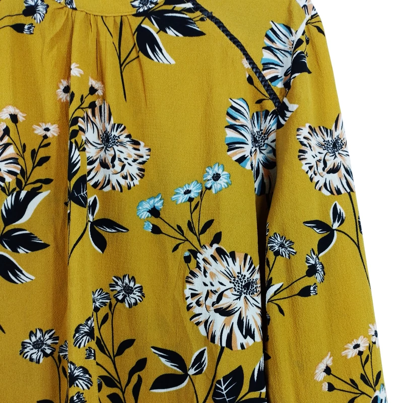 Nyakrészén hátul gombos, virágmintás női felső